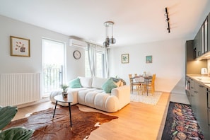 Ein modernes Wohnzimmer mit Sofa, Esstisch und Küchenbereich.