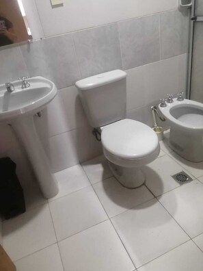 Une salle de bain équipée d’un lavabo, de toilettes, d’un bidet et d’un miroir.