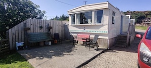 Ein Wohnmobil mit einer Terrasse, einem kleinen Tisch und Stühlen.