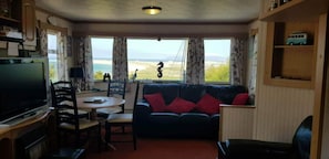 A compact living space with a television, a sofa, a dining table, and a view of the outdoors. - Mobile Homes Magheroarty Sleeps 5/6 With Garden (Gortahork)