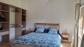 Une chambre à coucher avec un lit, une armoire en bois, des tables de chevet et une fenêtre avec des rideaux.