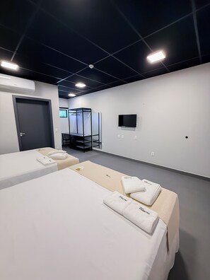 Una habitación de hotel con dos camas, un televisor y un espejo.