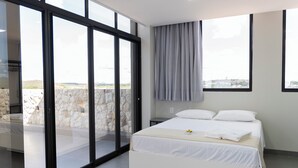 A modern bedroom with a large bed, a view through glass doors, and a stone wall outside. - Palhoça Hotel  (Canindé)