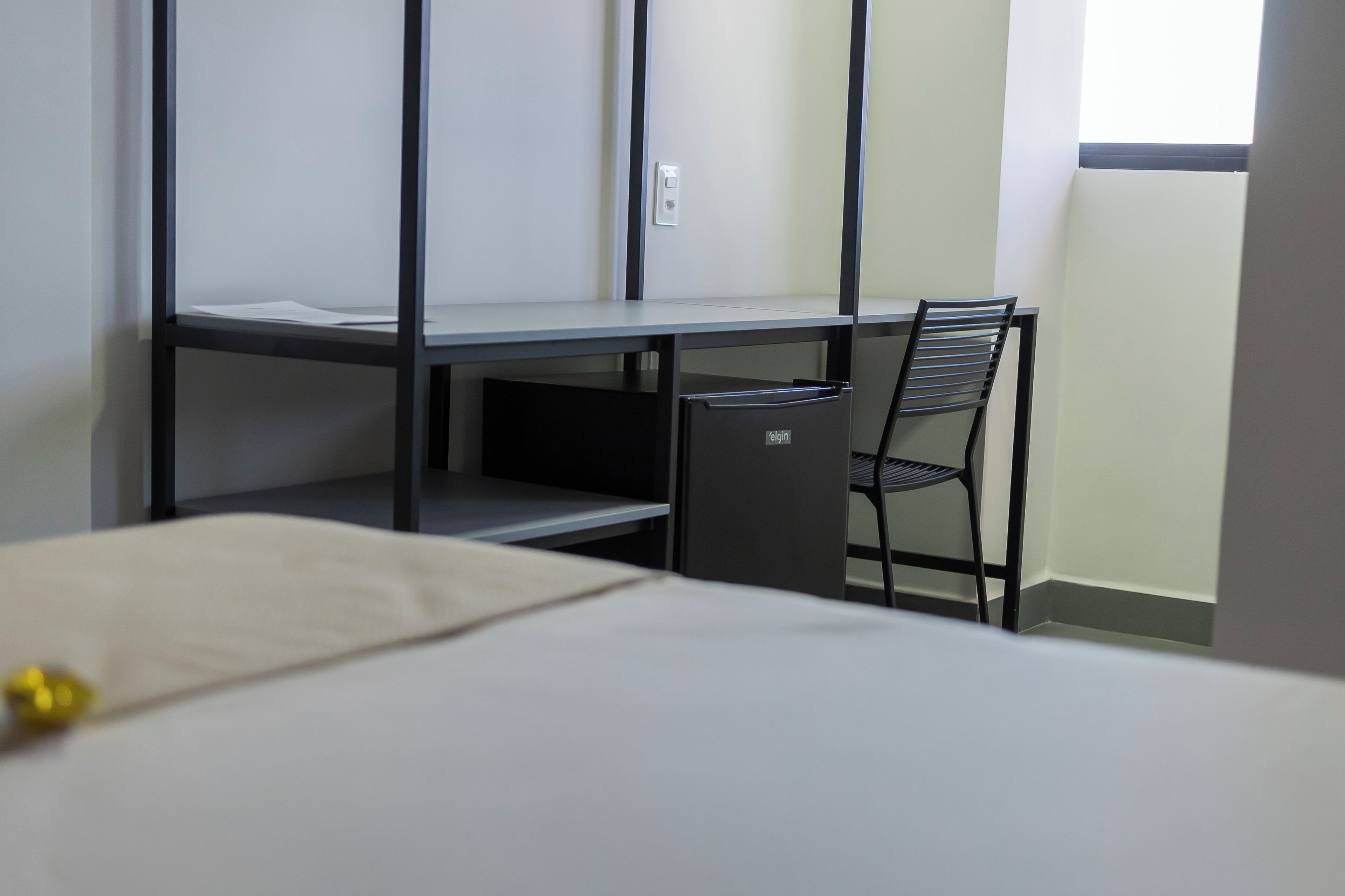 Une chambre avec un lit superposé, un bureau avec une chaise et une poubelle.