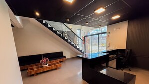 A modern interior with a staircase, a reception desk, and a seating area with a plant. - Palhoça Hotel  (Canindé)