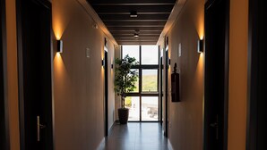 A long, narrow hallway with doors on both sides, recessed lighting, and a potted plant at the end. - Palhoça Hotel  (Canindé)