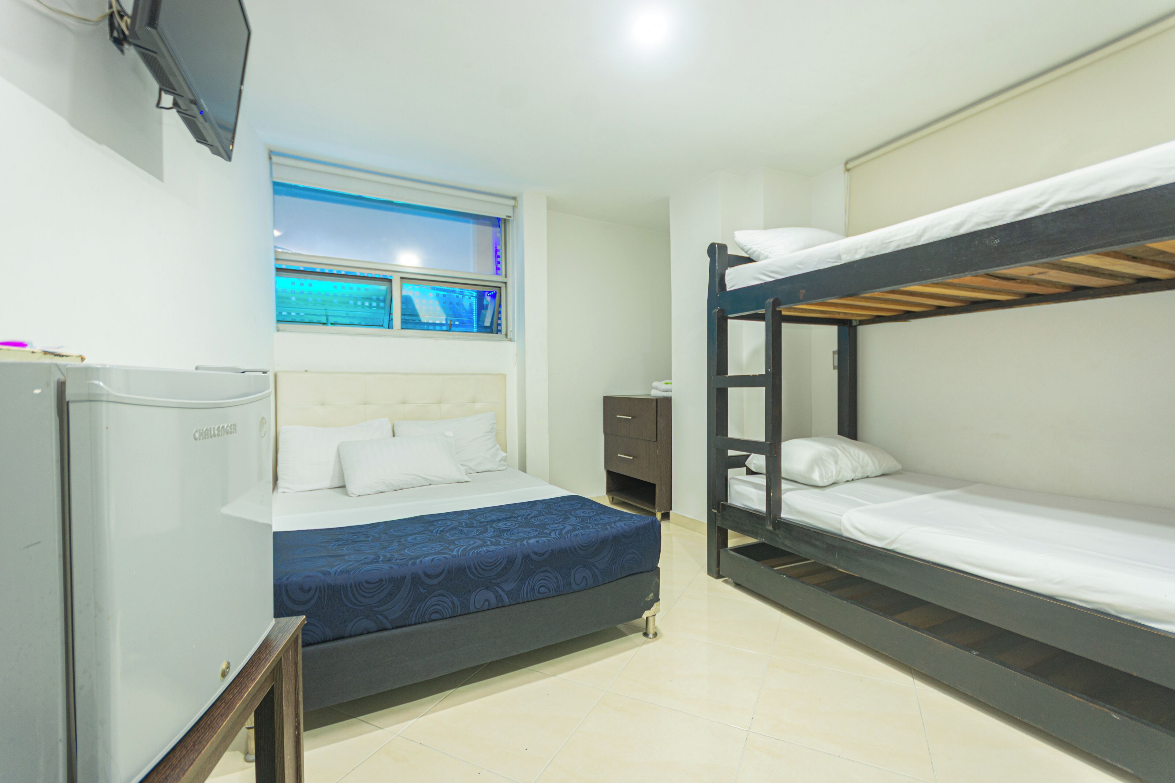 Una habitación con cama, escritorio, televisor y ventana con vista.