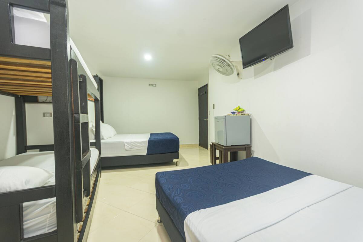 Habitación de hotel con literas, una cama individual, un televisor y un ventilador.