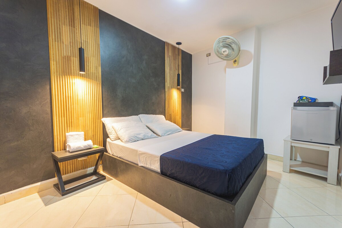 Un dormitorio moderno con cama, mesita de noche y ventilador de pared.