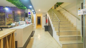 Un espace d’accueil comprenant un comptoir, un escalier et un couloir menant à une autre pièce.