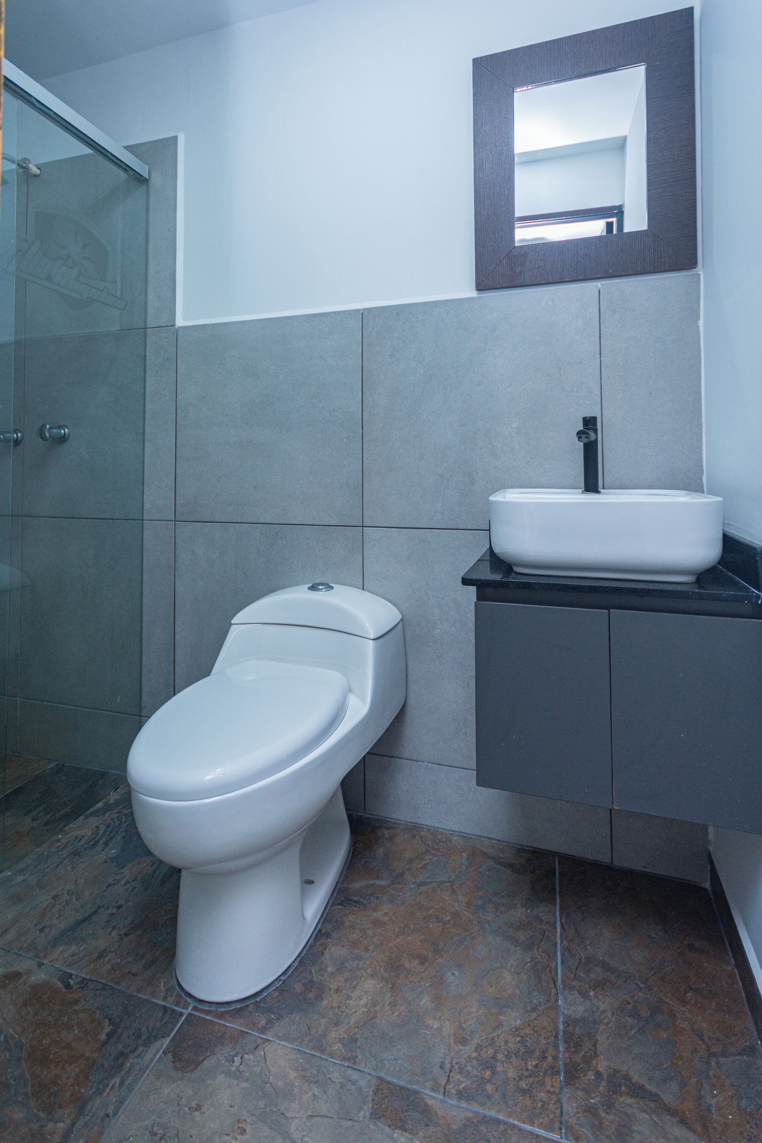 Une salle de bain avec des toilettes, un lavabo et un miroir au mur.