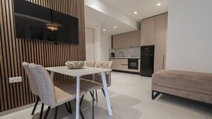 Uma cozinha moderna com forno embutido, geladeira preta e um espaço de jantar com mesa e cadeiras.