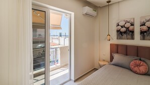 Quarto com cama, mesa de cabeceira, ar condicionado fixado na parede e porta para varanda.
