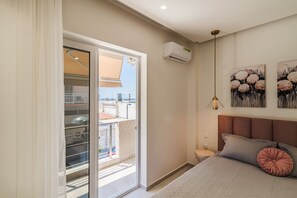 A bedroom with a bed, a nightstand, a wall-mounted air conditioner, and a balcony door. - Marianthi Home by Rentals Pro - Nea Moudania Halkidiki (Nea Moudania)