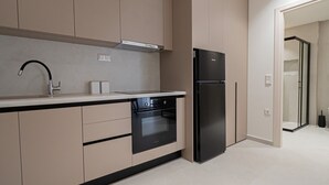 Uma cozinha moderna com forno embutido, geladeira preta e armários bege.