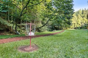 Ein Frisbee-Golf-Korb in einer grünen Umgebung mit Bäumen im Hintergrund.