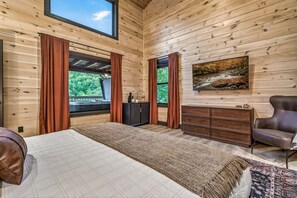 Ein Zimmer mit Holzwänden, einem Bett, einem Schrank, einem Sessel und einem Bild an der Wand.