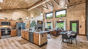 A spacious kitchen with wooden cabinets, a central island, and a dining area with a table and chairs. - Wellness & Wilderness - 3b/3.5 bath Family Retreat (Sevierville)