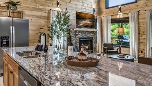 A kitchen with a granite countertop, a wine bottle, glasses, and a tray. - Wellness & Wilderness - 3b/3.5 bath Family Retreat (Sevierville)