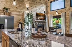 A kitchen with a granite countertop, a wine bottle, glasses, and a tray. - Wellness & Wilderness - 3b/3.5 bath Family Retreat (Sevierville)
