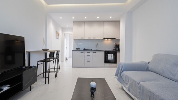 A modern living room with a TV, sofa, and a dining area with chairs. - Dimitra Home by Rentals Pro - Polychrono Halkidiki (Polychrono)