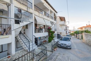 Ein Wohngebäude mit Treppe, Balkonen und einem parkenden Auto.