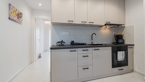 A modern kitchen with a marble backsplash, a built-in oven, and a coffee maker. - Dimitra Home by Rentals Pro - Polychrono Halkidiki (Polychrono)