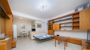 Une pièce de taille modeste, comprenant un lit, un bureau, une chaise, une petite table et des étagères en bois intégrées.