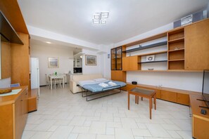 Ein kleines Zimmer mit Bett, Schreibtisch, Stuhl, einem kleinen Tisch und integrierten Holzbögen.