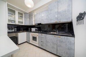 Eine moderne Küche mit Marmor-Schränken, einer schwarzen Arbeitsplatte und einem eingebauten Backofen.