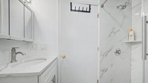 Une salle de bain équipée d’un lavabo, d’un miroir, d’une douche et d’un porte-serviettes.