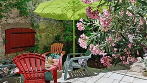 Eine Terrasse mit Gartenmöbeln, einer Steinmauer und blühenden Pflanzen.
