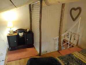 Ein Zimmer mit einem Bett, einem Schreibtisch mit Lampe, einer herzförmigen Dekoration an der Wand und einer Treppe.