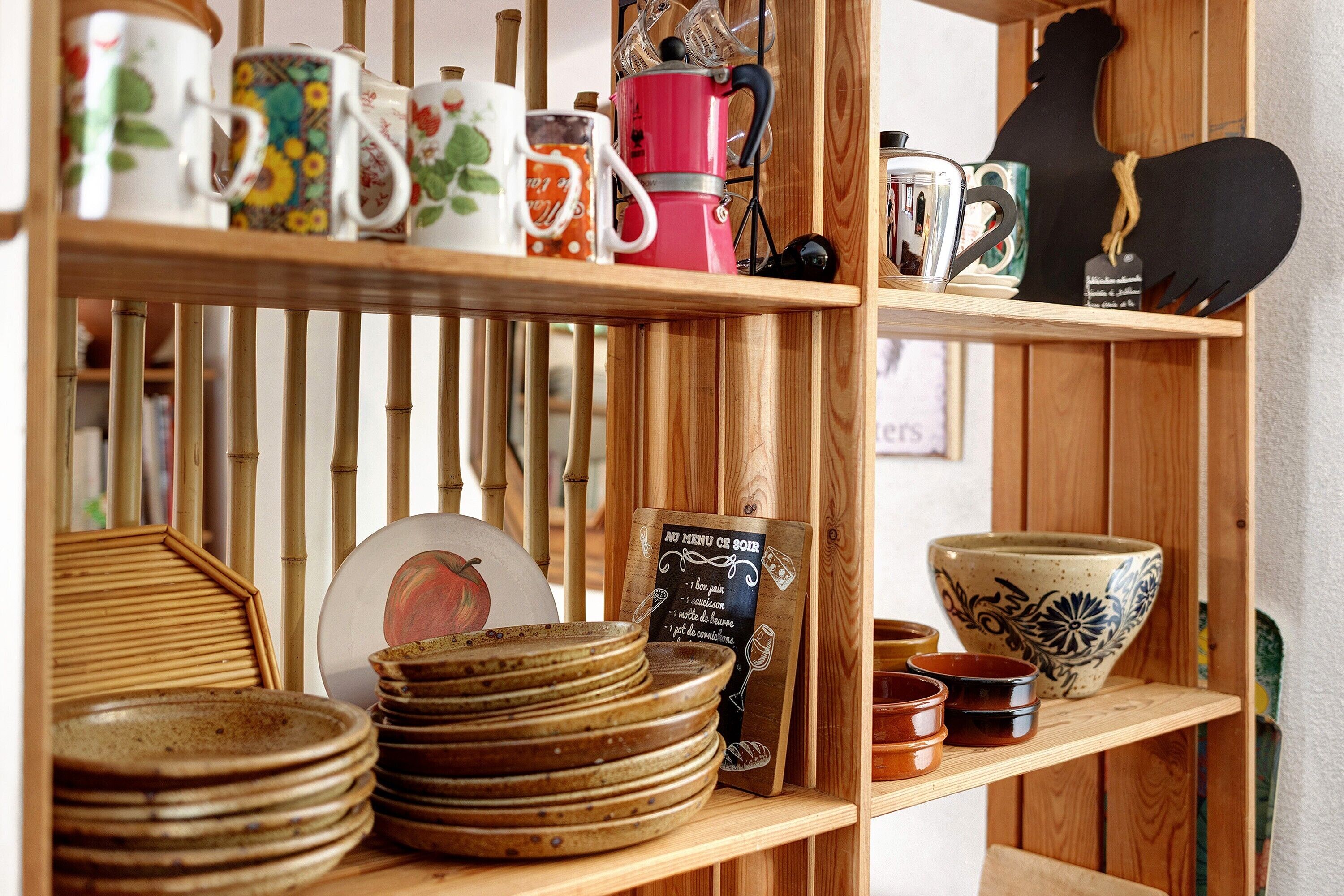 Een houten plank met divers keukengerei, zoals borden, mokken en een koffiezetapparaat.