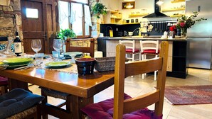 Ein Essbereich mit Holztisch, Stühlen und einer Küche im Hintergrund.
