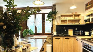 Eine moderne Küche mit Holzschränken, einer großen Kochinsel, einem Einbauofen und einer Wand mit Natursteinverkleidung.