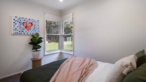 A bedroom with a bed, a window, a plant, and a wall art piece. - Hepburn Woodland Retreat (Dry Diggings)