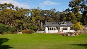 A house with a large lawn, a fenced yard, and a forested backdrop. - Hepburn Woodland Retreat (Dry Diggings)