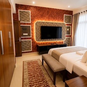 Ein Hotelzimmer mit einem großen Bett, einem an der Wand befestigten Fernseher, einem Holzschrank und einem gemusterten Teppich.