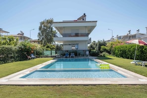 Ein modernes, zweistöckiges Gebäude mit einem Pool im Vordergrund.