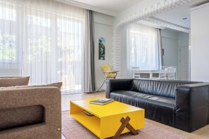 Ein modernes Wohnzimmer mit einem schwarzen Ledersofa, einem gelben Couchtisch und einem braunen Sessel.