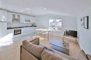 A modern apartment with a kitchen, dining area, living room, and a TV. - Myra - 3 Bed Duplex with garden view (Antalya)