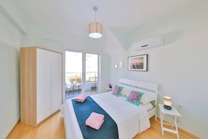 A bedroom with a bed, bedside table, lamp, air conditioning unit, and a view to the outside. - Myra - 3 Bed Duplex with garden view (Antalya)