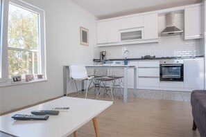 A modern kitchen with white cabinets, a built-in oven, and a window with a view of trees. - AMADO - 3 Bed Duplex with view on pool (Antalya)