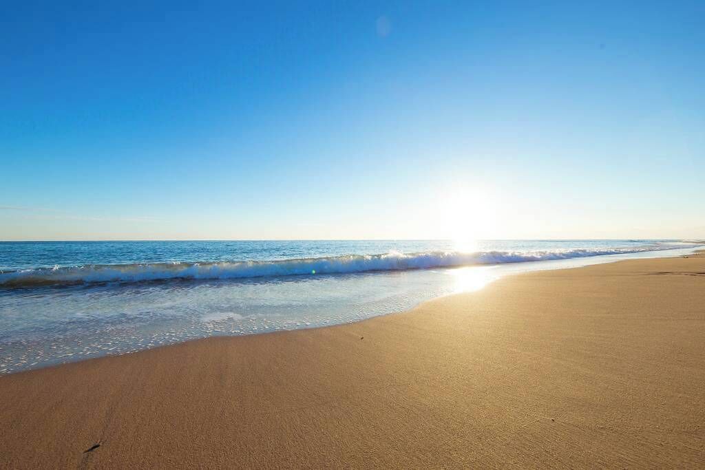 A beach with a clear sky and sunlight reflecting off the water.