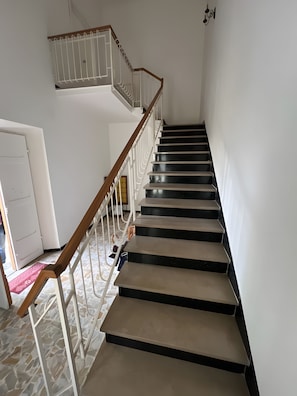 Una escalera con barandilla de madera y balaustres blancos, que conduce a un piso superior.