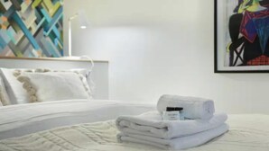 A neatly made bed with a folded white towel and a bottle of lotion on it. - JUST A SHORT WALK FROM THE ICONIC CENTRE POMPIDOU- LE MARAIS (Paris)
