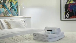 A neatly made bed with a folded white towel and a bottle of lotion on it. - JUST A SHORT WALK FROM THE ICONIC CENTRE POMPIDOU- LE MARAIS (Paris)