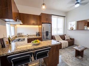 A modern kitchen with granite countertops, wooden cabinets, a built-in gas stove, a refrigerator, and a coffee maker. - Las Canoas Zona Romantica By Monyxbnb  (Puerto Vallarta)