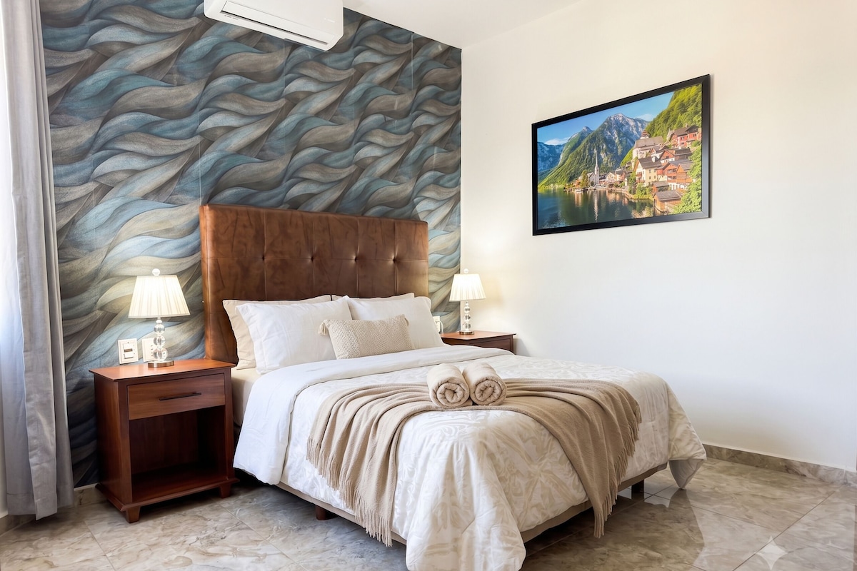 Een slaapkamer met een bed, nachtkastjes, een wandairconditioner, een schilderij en een marmeren vloer.